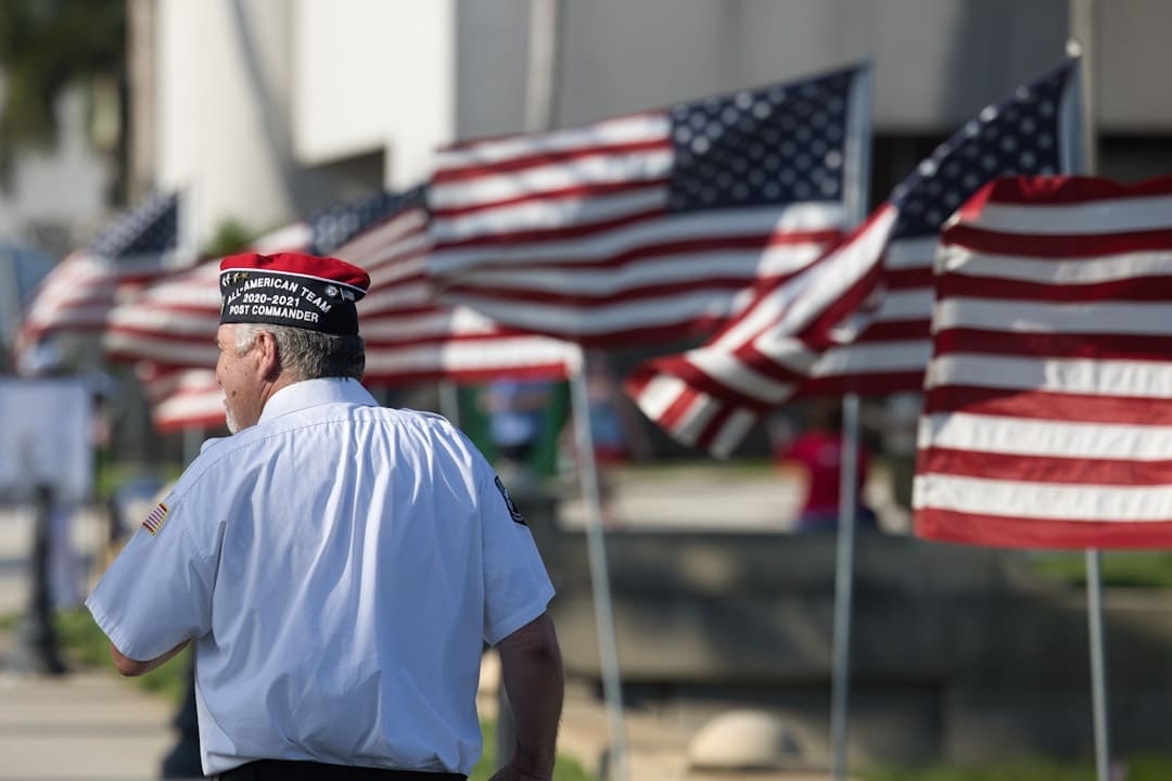 service dog retirement — a man standing in front of a row of american flags